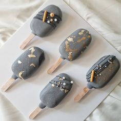 four ice cream pops decorated with gold and silver designs on top of a white board