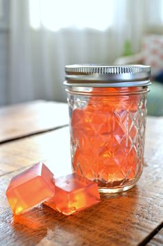 a glass jar filled with orange colored rocks on top of a wooden table