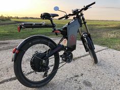 an electric bike parked on the side of a road near grass and trees in the background