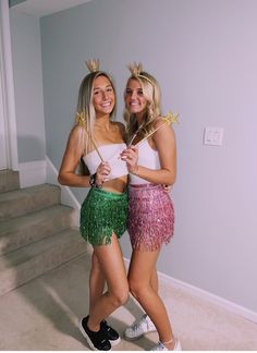 two young women dressed in costumes standing next to each other with wands on their heads