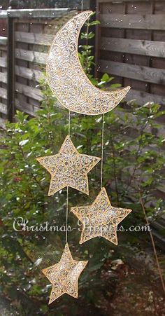 a wind chime with three stars hanging from it's side in front of a fence