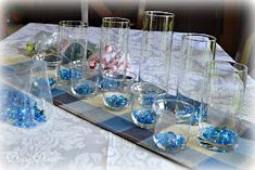 there are many glass vases on the table with blue balls in them and candy