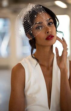 a woman wearing a veil and holding her hand to her face while looking at the camera