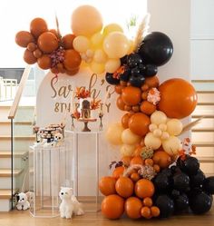 a bunch of balloons that are on top of a table in front of some stairs