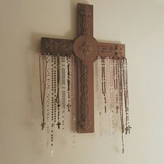 a cross with beads hanging from it's side on the wall next to a window