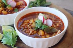 two bowls filled with soup and garnished with radishes on a cutting board