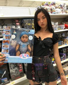 a woman holding up a doll in a store