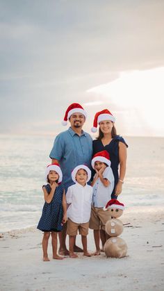 a family poses on the beach in santa hats