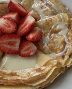 a plate topped with pancakes covered in syrup and sliced strawberries