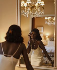 a woman in a white dress looking at herself in the mirror