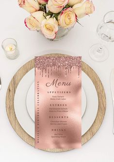 a table setting with pink and gold place settings, silverware, and roses in a vase