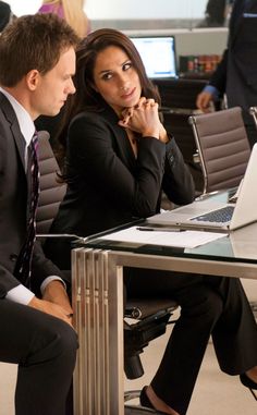 two people sitting at a table with laptops