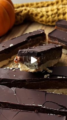 pieces of chocolate and marshmallows on a cutting board with a pumpkin in the background