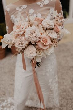 a woman holding a bouquet of flowers in her hand and wearing white pants with lace on them