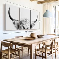 a dining room table with four chairs and two cows on the wall behind it in black and white