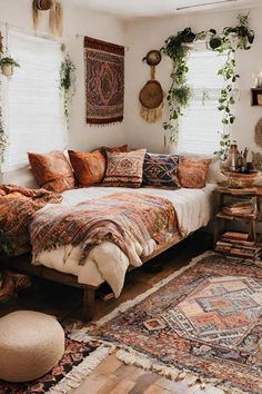 a bed with lots of pillows on top of it in a room filled with plants