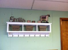 a white shelf with baskets on top of it and a stuffed animal sitting on top of it