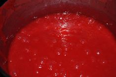 a red pot filled with liquid on top of a stove