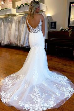 a woman in a white wedding dress standing on a wooden floor looking back at the camera