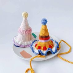 two crocheted hats sitting on top of a white plate next to each other