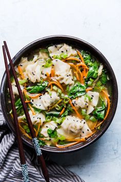 a bowl filled with dumplings and vegetables next to chopsticks