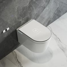 a white toilet sitting on top of a bathroom floor next to a gray tiled wall