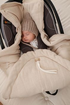 a baby sleeping in a stroller with a blanket over it's head and hood