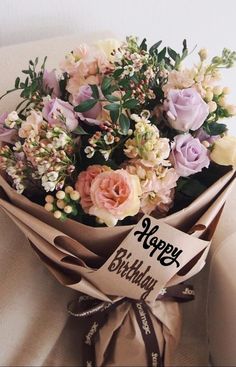 a bouquet of flowers wrapped in brown paper with a happy birthday sign on the side