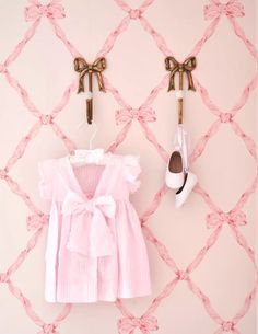 two pairs of shoes hang on the wall next to a pink shirt and bow tie