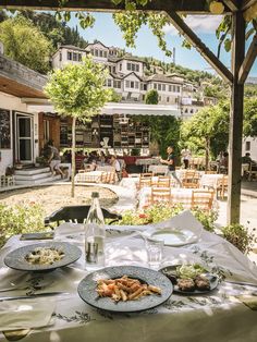 an outdoor dining area with food and drinks on the table, in front of a house