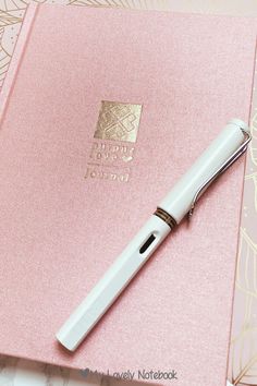 a pink notebook with a fountain pen on top