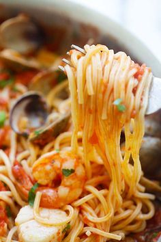 a spoon full of pasta with shrimp and tomato sauce