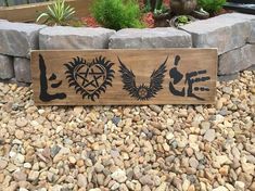 a wooden sign sitting on top of a pile of rocks next to a planter