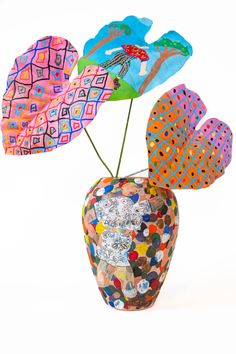 a vase filled with colorful paper flowers on top of a white table