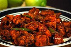 a white plate topped with meat covered in sauce next to green peppers and an apple