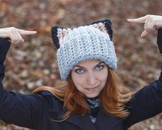 a woman with red hair wearing a knitted hat and pointing to the left side