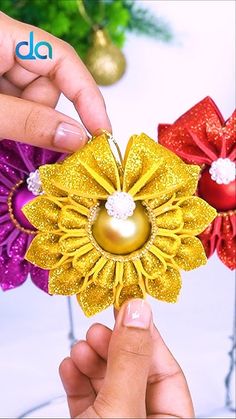 two hands are holding an ornament made out of paper flowers and other decorations