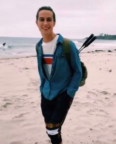 a young man standing on top of a sandy beach