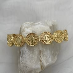 Gorgeously unique, this stunning medal coin cuff bracelet is perfect for wearing alone or stack with some of our gold fill bead bracelets. The Benedictine Medal is one of the most powerful symbols of divine protection. Wear this petite bracelet as a reminder that you are protected by God's army and as St Benedict did, to do good every day.  Tradition holds that it stands for the power of prayer in times of temptation and suffering, wards against evil, and symbolizes how prayer creates peace within ourselves and in our communities. Specifications - Adjustable cuff, one size fits most, up to wrist size 7.5 18kt gold plated or sterling silver plated God's Army, Czech Beads Jewelry, Catholic Bracelet, Powerful Symbols, Petite Necklace, The Power Of Prayer, Divine Protection, Dainty Gold Bracelet, St Benedict