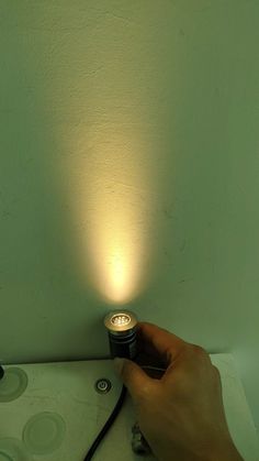 a person is holding a small light in their hand, on top of a table