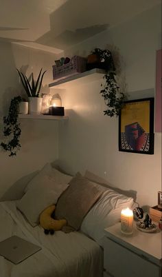 a bed with white sheets and pillows next to a shelf filled with plants on top of it