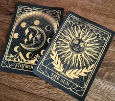 two tarot cards sitting on top of a wooden table with the sun and moon