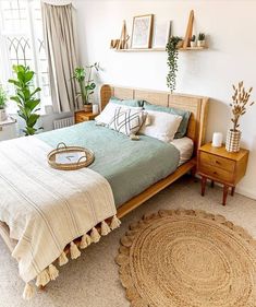 a bed room with a neatly made bed and lots of plants on the windowsill