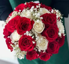 a bouquet of red and white roses is held by a woman's hand in a green dress