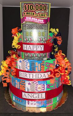 a multi - tiered birthday cake made out of candy wrappers with ribbons around it