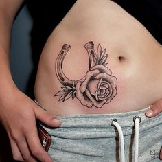 a woman's stomach with a rose tattoo on the side and an anchor in the middle