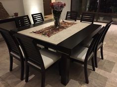 a dining room table with chairs and a vase filled with flowers on top of it