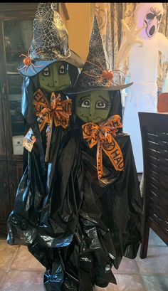 two witches in black plastic bags with orange bows on their heads, standing next to each other