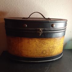 an old black and yellow suitcase sitting on top of a table next to a wall