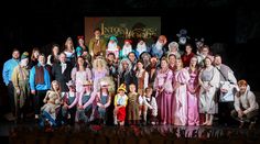 a group of people dressed in costumes posing for a photo on stage with the characters from disney's beauty and the beast